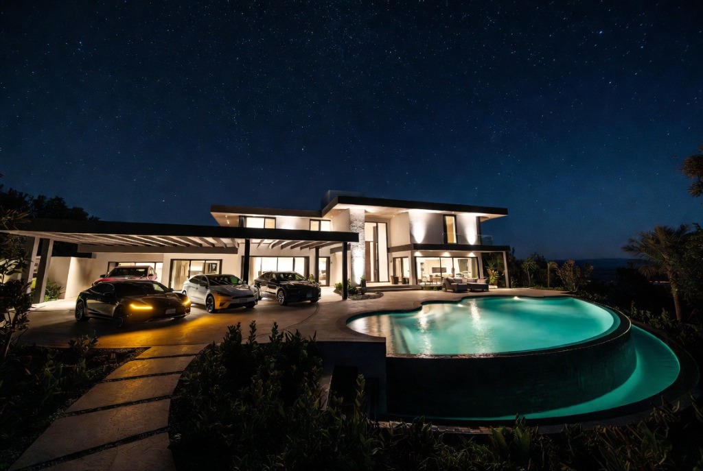 A modern home glowing beside a pool at night